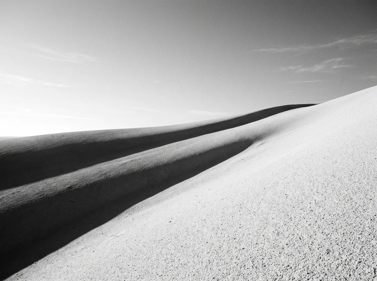 Ombres longues et bleues projetées sur la surface lisse d'une dune de craie blanche, lumière rasante du matin, détails de grain fin de craie